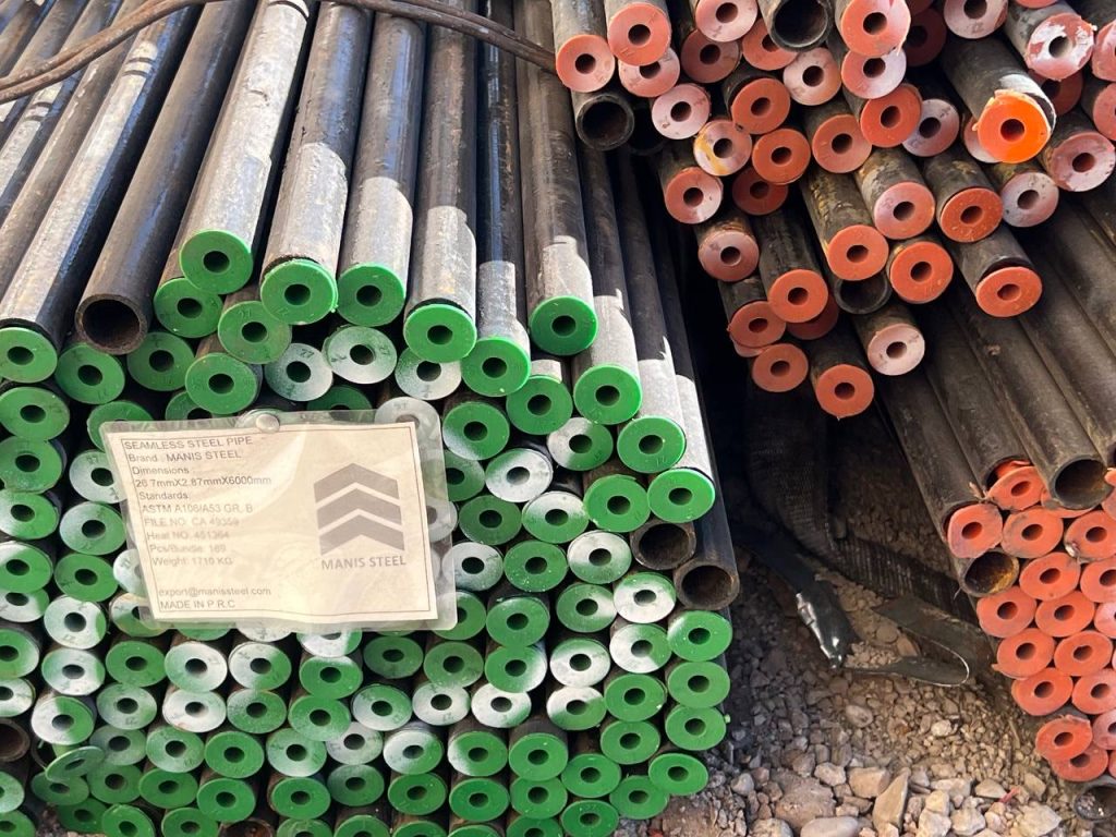 برچسب MANIS STEEL با ابعاد 26.7mm، درپوش‌های سبز و نارنجی در دو طرف تصویر