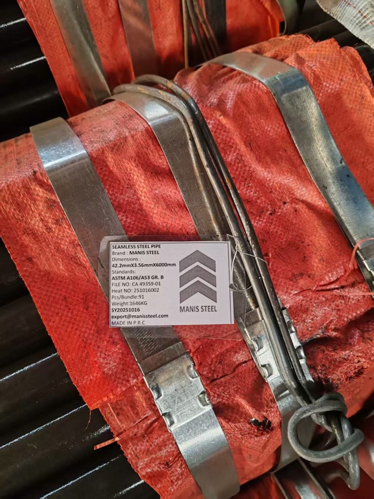 برچسب واضح MANIS STEEL با ابعاد 42.2mm، استاندارد ASTM A106/A53، روی دسته لوله پیچیده در گونی نارنجی