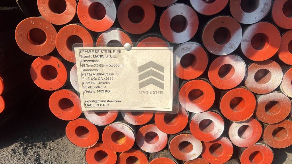 نمای نزدیک برچسب MANIS STEEL روی دسته لوله با درپوش‌های نارنجی، مطابق استاندارد ASTM A106/A53