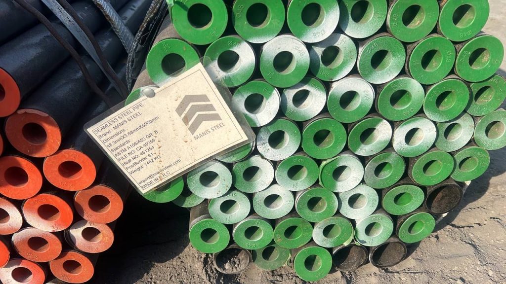 برچسب فنی MANIS STEEL با مشخصات ASTM A106/A53 روی دسته لوله با درپوش‌های سبز و نارنجی